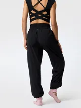 Pantalón de microfibra negro, de corte estilo bombacho y silueta relajada, con cintura y puños elásticos fruncidos. Presenta costuras frontales verticales y bolsillos funcionales.