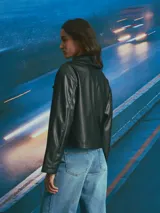 Chaqueta corta de cuero sintético en color negro, con diseño de doble botonadura, solapas amplias y corte holgado.