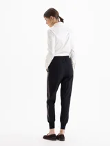 Pantalon sastrero negro con diseño tipo jogger, cuenta con bolsillos delanteros, bolsillos ojal traseros, cinta lateral de cuero y puños tejidos en ribb en el ruedo.