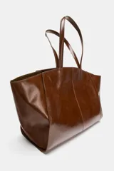 Bolso tipo shopper confeccionado en piel, con diseño de doble asa de hombro y cierre mediante botón imantado. Incluye bolsillo interior.