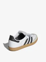 Zapatillas Adidas Samba LT blancas con las tres tiras negras y suela de goma color caramelo.