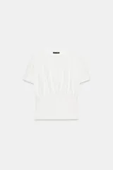 Camiseta blanca de algodón con cuello redondo, manga corta y diseño ajustado en la cintura tipo corset.
