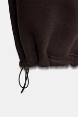 Pantalón de felpa de tiro alto con cintura elástica y corte recto. Cuenta con bolsillos laterales ocultos en la costura y bajo ajustable con cordón elástico y stoppers.