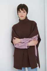 Poncho de tejido de punto color caramelo con cuello alto y diseño holgado sin mangas.