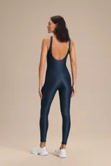 Jumpsuit largo de diseño ajustado con escote redondo y espalda descubierta, confeccionado en tejido satinado con textura acanalada. Presenta copas extraíbles y tecnología de compresión media que se adapta al cuerpo.