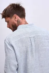 Camisa de manga larga para hombre, con cuello clásico y botones frontales. Presenta un estampado de rayas verticales finas en tonos azul claro y blanco.