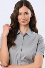 Camisa celeste rayada de manga corta, con cuello camisero y cierre frontal con botones. Presenta un corte entallado y un pequeño detalle de placa metálica en el borde inferior.