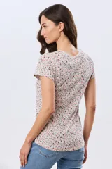 Remera blanca de manga corta con estampado floreado, cuello redondo y detalle de botones frontales.