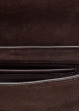 Bolso de hombro tipo baguette confeccionado en piel de serraje color marrón oscuro. Presenta un diseño rectangular con cierre de solapa y detalle metálico frontal. Incluye forro interior y bolsillo interno.