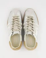 Championes de estilo retro con acabado metalizado plateado, detalles en cuero color crema y suela de goma color caramelo. Presentan cordones al tono y refuerzo en el talón.