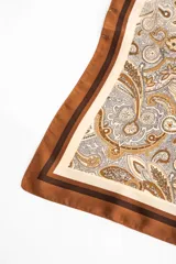 Pañuelo de poliéster de forma cuadrada, con diseño estampado estilo paisley en tonos marrones, beige y blanco, y bordes enmarcados en marrón.