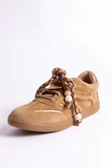 Zapatillas urbanas de gamuza color marrón, con diseño de cordones decorados con cuentas de piedra y detalles de líneas brillantes en los laterales. Presentan suela de goma texturizada al tono.