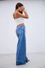 Jean de corte wide leg con tiro medio, confeccionado en denim rígido sin elastano. Presenta un diseño de paneles con costuras verticales y un ruedo con detalle de costura horizontal y terminación desflecada.