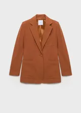 Chaqueta color marrón con cuello de solapa, manga larga con puños abotonados, dos bolsillos frontales de parche, un bolsillo de parche en el pecho, abertura posterior en el bajo y forro interior.