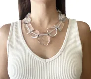 Collar corto con cordón negro y grandes cuentas facetadas de resina transparente con formas geométricas variadas.