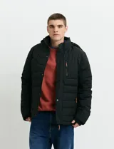 Campera puffer verde militar de cuello alto, con cierre frontal y solapa con broches a presión. Cuenta con bolsillos laterales y un bolsillo vertical en el pecho con cierre, ambos con tiradores naranjas.