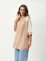 Remera oversize de manga corta con escote en V, de diseño bicolor en tonos beige y tostado, con mangas raglán y corte amplio.