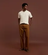 Camisa de punto color marrón con textura acanalada y perforaciones. Presenta cuello polo con cierre de cremallera frontal y mangas cortas.