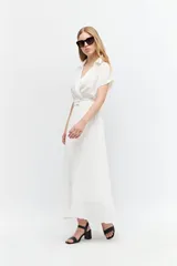 Vestido midi blanco con cuello camisero, escote en V, mangas cortas y falda plisada. Incluye cinturón con hebilla forrada.