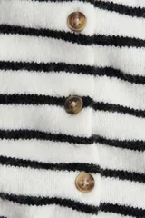 Saco corto de punto fino suave, color blanco con rayas horizontales negras. Presenta escote redondo, botones frontales y remate acanalado en puños y bajo.