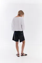 Bermuda de denim negro tipo jeans, con tiro medio, bolsillos traseros con bordado en contraste y ruedo desflecado.