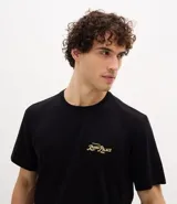 Remera masculina negra de algodón, corte comfort, con cuello redondo y mangas cortas. Presenta una estampa lettering con follaje "Royal Palace" en amarillo en el frente y la espalda.
