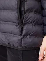 Campera acolchada tipo puffer color negro, con capucha, cierre frontal y bolsillos laterales con cierre. Presenta un diseño de costuras horizontales y logo de la marca en el pecho.