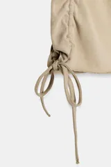 Camiseta corta de cuello redondo y manga corta, color gris oscuro, con frunces laterales ajustables mediante cordones.