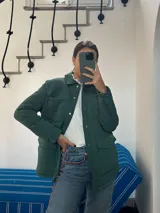 Campera verde militar acolchada con cuello camisero, cierre frontal con botones a presión, bolsillos de parche con solapa en el pecho y bolsillos laterales.