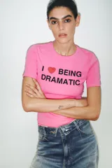 Camiseta rosa de cuello redondo y manga corta con estampado frontal de la frase "I ❤️ BEING DRAMATIC" con strass. Corte slim fit.