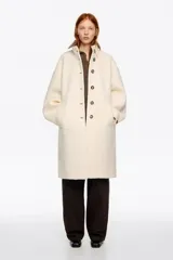 Abrigo midi de estructura envolvente confeccionado en mezcla de lana doble faz. Presenta cuello subido, cierre frontal con botones, mangas largas amplias con ajuste de botón en el puño y bolsillos laterales de vivo.