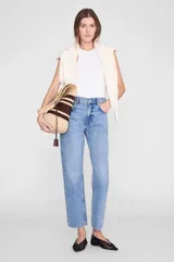 Bolso tipo hobo Anine Bing confeccionado en rafia 100% natural, con diseño a rayas en tonos beige y marrón. Cuenta con tiras de hombro integradas, detalle de tiras de cuero colgantes y un pequeño monograma metálico dorado en la parte frontal.
