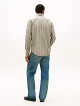 Camisa de manga larga Tommy Hilfiger de corte regular, confeccionada en popelín de algodón color beige con rayas verticales texturizadas en tonos blancos y oscuros. Presenta cuello con botones, puños redondeados y el logo de la marca bordado en el pecho.