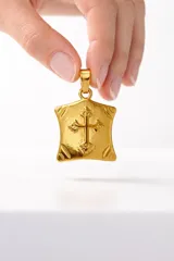 Dije de acero dorado con forma rectangular de bordes cóncavos y relieve de cruz central.