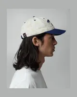 Gorra TwoJeys de diseño con estampado all-over de estrellas en tonos claros y visera azul marino. Presenta el nombre de la marca y dos estrellas bordadas en azul marino en el frente.