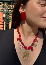 Collar corto compuesto por cuentas de resina en tono crema con acabado marmolado, adornado con múltiples dijes colgantes de acero dorado que incluyen una medalla de la Virgen Milagrosa, una cruz y un dije circular con flores pintadas.