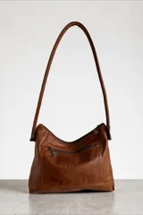 Cartera de cuero 100% natural color marrón, con diseño de hombro, cierre superior y detalles de arte pintado en la parte inferior.