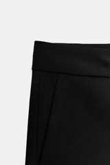 Shorts negros de tiro bajo, corte ajustado y muy corto, con bolsillos delanteros y cierre frontal con cremallera y gancho metálico.