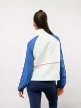 Campera deportiva Umbro del Club Nacional de Football, con diseño de bloques de color en azul marino y blanco. Presenta cuello alto, cierre frontal completo, bolsillos laterales y el escudo del club junto al logo de la marca en el pecho.