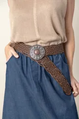 Cinto ancho de cuero trenzado color marrón, con hebilla redonda metálica de estilo envejecido y centro de piedra marrón.