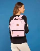 Mochila Cabaia modelo Adventurer Hanoi M, color rosado, con diseño rectangular, doble asa superior, bolsillo frontal con cierre y parches circulares y rectangulares con logo de la marca.