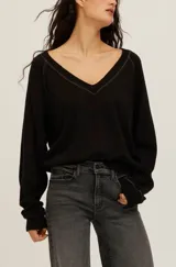 Sweatshirt Cambridge de felpa ligera en color negro, con corte holgado y escote en V pronunciado con ribetes en contraste. Presenta mangas largas con puños ajustados y costuras visibles.