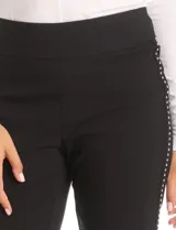 Pantalón slim fit de tiro alto con pretina ancha elastizada y detalle de hilera vertical de micro-tachas metálicas en los laterales. Diseño al tobillo con ruedo recto.
