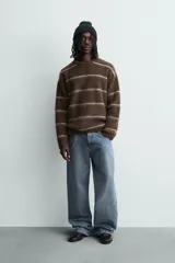 Jersey de punto con textura, corte relajado, cuello redondo y manga larga. Presenta un diseño de rayas horizontales en tonos marrones y grises con acabados en rib.
