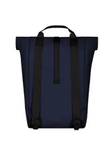 Mochila azul marino con sistema de cierre enrollable y hebilla de ajuste. Tiene un bolsillo frontal con logo de la marca, tres tiras horizontales con presillas y asa superior.