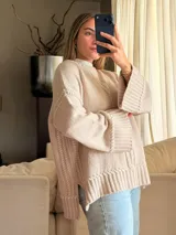 Sweater de punto oversize color beige, con cuello redondo, mangas largas acampanadas y detalles de bordado artesanal en relieve a lo largo del frente y las mangas.