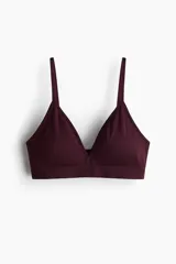 Soutien de diseño seamless, color bordó, con copas triangulares forradas, relleno extraíble y breteles finos ajustables. Presenta una banda elástica inferior ancha para mayor sujeción y un diseño sin aros ni cierres.