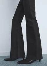 Pantalón de jean estilo flare de tiro medio, con cierre frontal de cremallera y botón, diseño de cinco bolsillos y acabado con bajo desflecado.