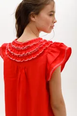 Vestido negro de lino, corte suelto, con cuello redondo con volados y mangas cortas con volados.