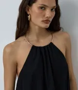 Body de microfibra color negro con diseño de frente única y detalle de adorno metálico tipo collar en el cuello. Presenta una caída fluida y espalda descubierta, ideal para un look sofisticado.